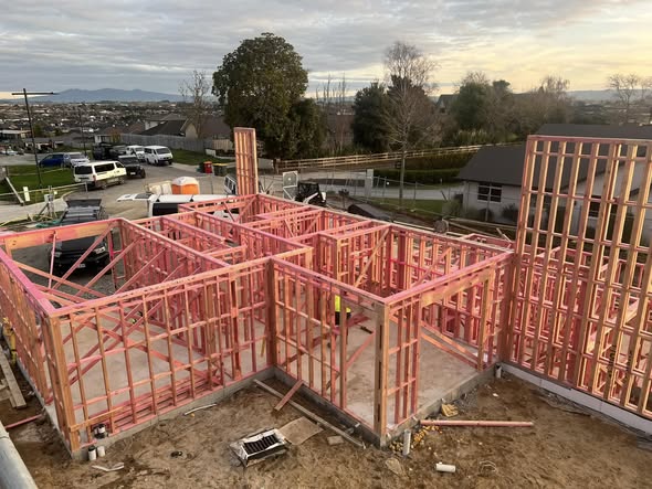Pink H1.2 timber framed two-storey home on a Hamilton ridge at golden hour